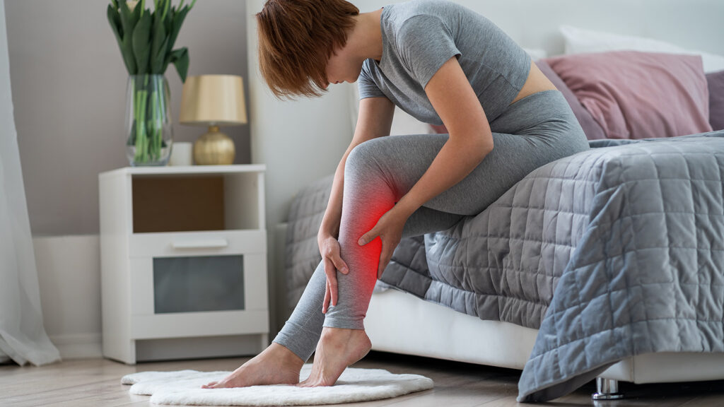 Femme avec une crampe au mollet obligée de s'assoire