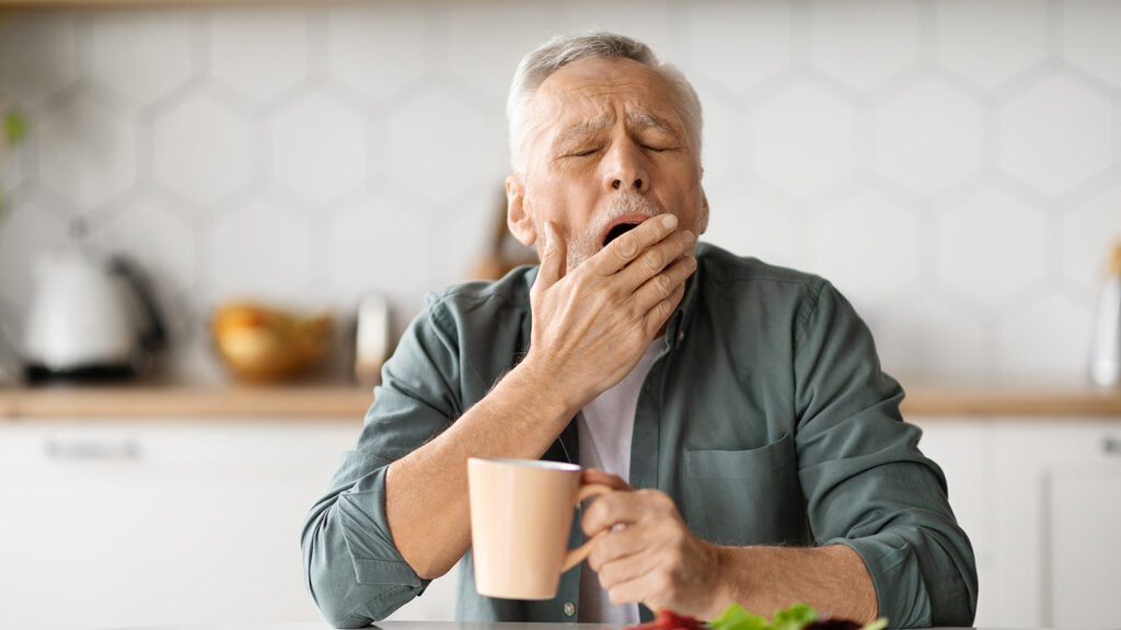 Homme âgé bâillant, symptomatique de la somnolence diurne liée à l'apnée du sommeil