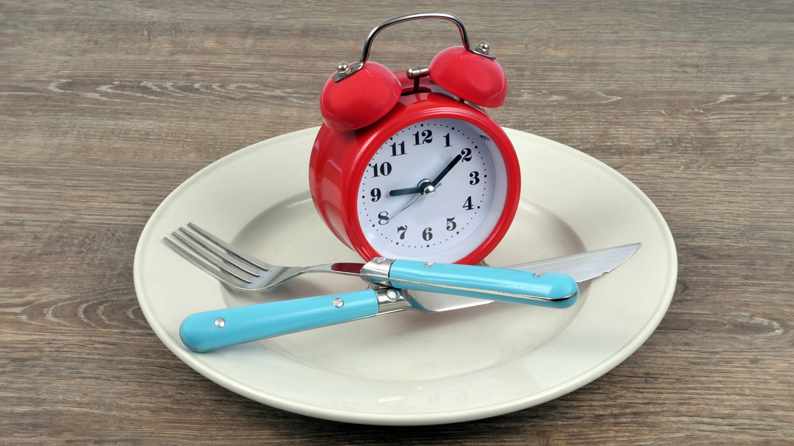 Horloge sur une assiette avec des couverts, illustrant le concept de la chronobiologie des repas.