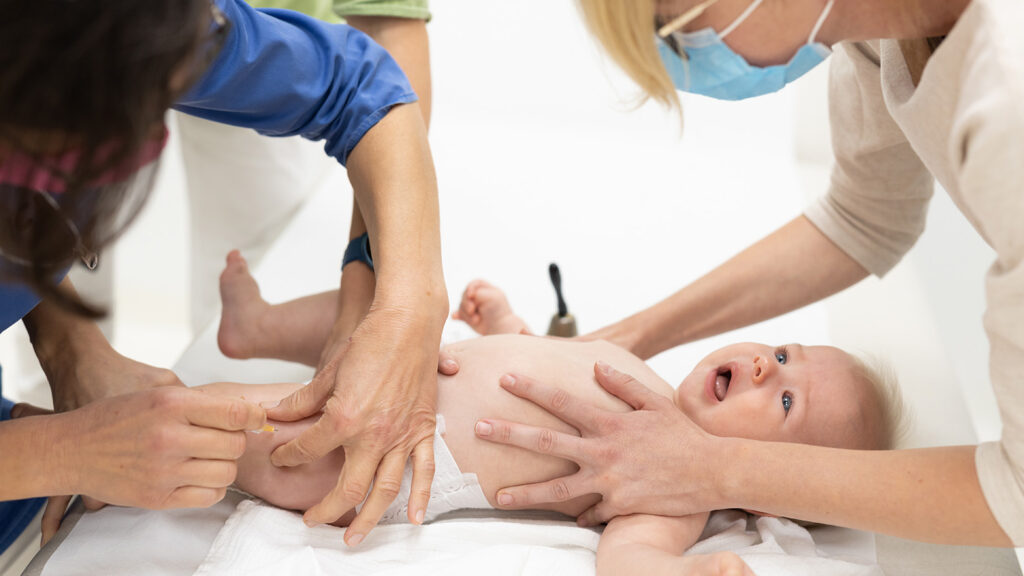 Nourrisson recevant un vaccin contre le pneumocoque sous le regard attentif des parents et d'un professionnel de santé.