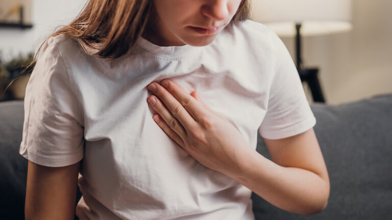 Femme tenant sa poitrine pour indiquer une gêne respiratoire.