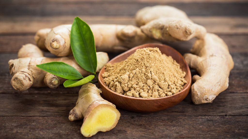 Racine de gingembre fraîche à côté de sa poudre moulue et capsules de complément.