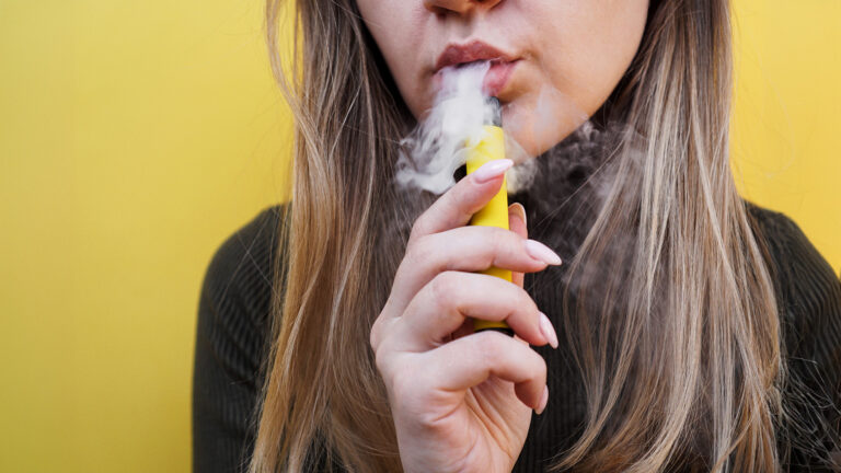 Personne utilisant une cigarette électronique et exhalant de la vapeur.