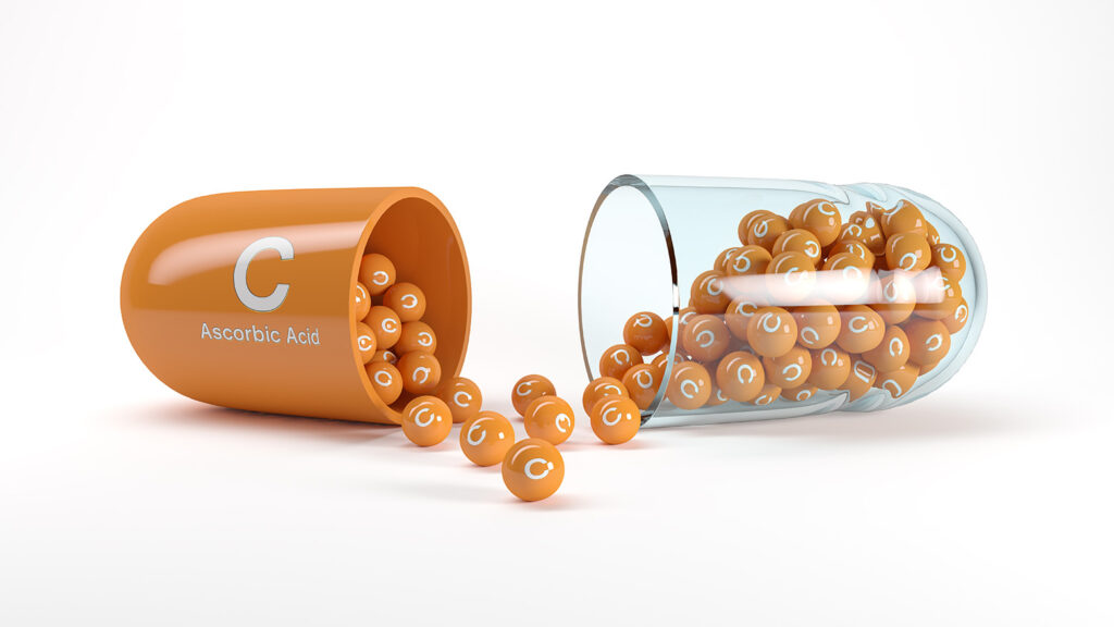 Capsules de vitamine C ouvertes avec des billes orange marquées ‘C’ à l’intérieur