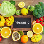 Fruits et légumes variés autour d’une ardoise avec l’inscription ‘Vitamine C’.