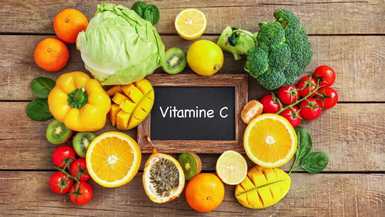 Fruits et légumes variés autour d’une ardoise avec l’inscription ‘Vitamine C’.