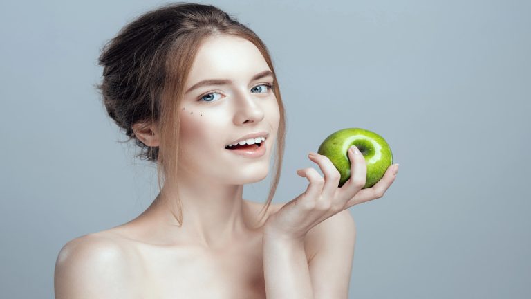 Une femme mange une pomme verte