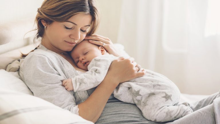 Mère tenant tendrement son nouveau-né contre elle.