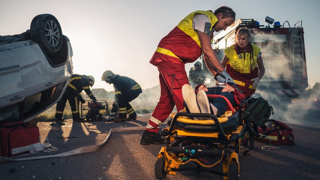 Secours sur le lieu d'un accident avec une voiture retournée.