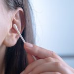 Personne utilisant un coton-tige pour nettoyer l'oreille.
