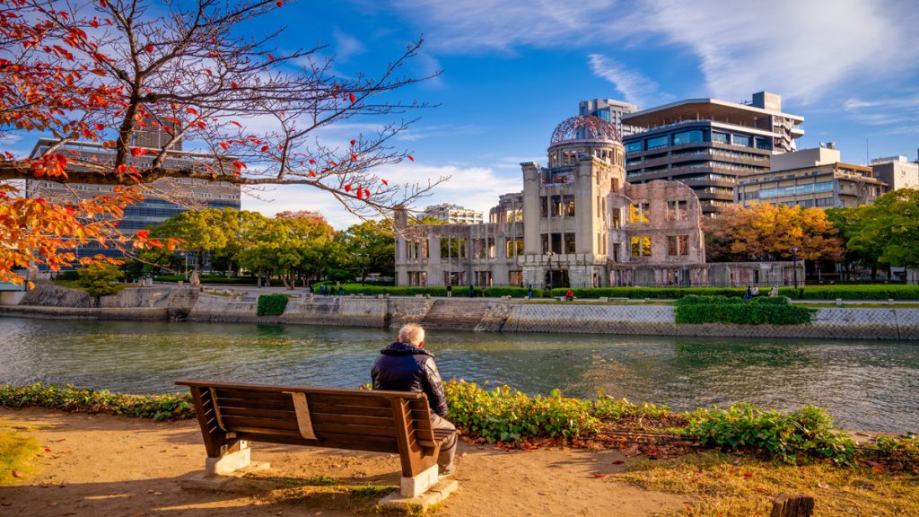 Homme assis sur un banc regardant le seul batiment intact d'Hiroshima au Japon.