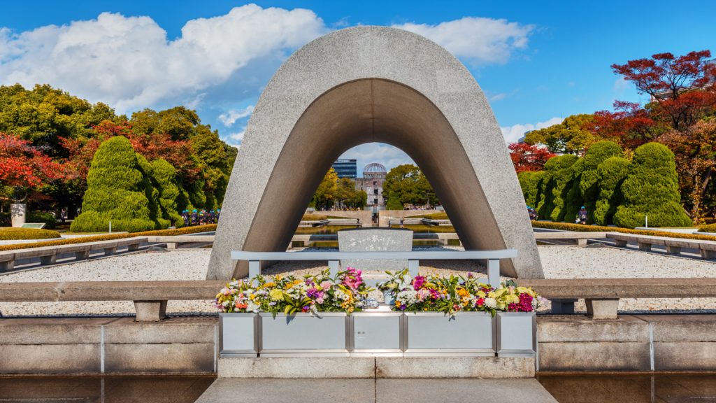 Cénotaphe commémoratif à Hiroshima avec des fleurs déposées devant.