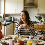 Une famille souriante partage un repas dans une cuisine conviviale.