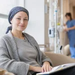 Une femme portant un foulard, assise dans un fauteuil, dans un environnement médical.